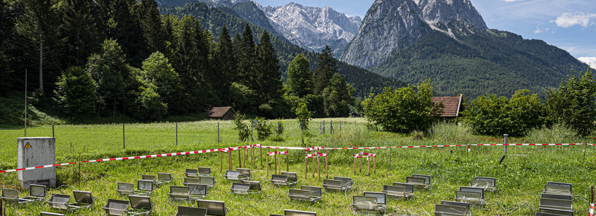 You can see a grassy area against the backdrop of the Zugspitze and the Waxenstein. A large-scale scientific test set-up consisting of dynamic measuring chambers for climate gas measurements can be seen on the grass.