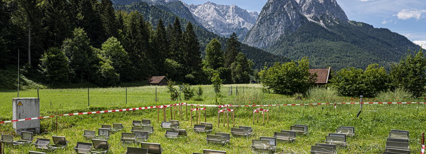 Automated static chamber system for greenhouse gas source strength determination. Photo: KIT (Markus Breig) You can see a grassy area against the backdrop of the Zugspitze and the Waxenstein. A large-scale scientific test set-up consisting of dynamic measuring chambers for climate gas measurements can be seen on the grass.